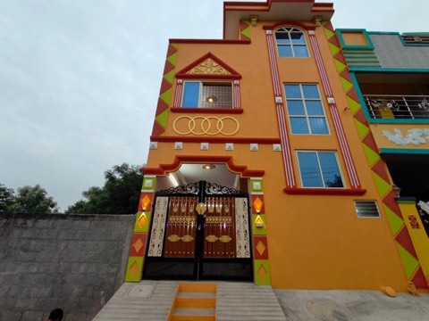 Completed two-storey house with orange and red elevation, painted diamond trim and a black metal gate, VK Builders project