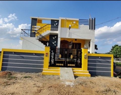 Completed yellow, white and grey modern house with black exterior staircase and ornate black gate, VK Builders project