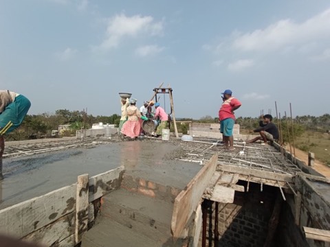 Construction team casting a roof slab with rebar mesh and formwork visible, VK Builders site