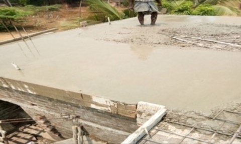 Freshly poured roof slab being finished by a worker, VK Builders site