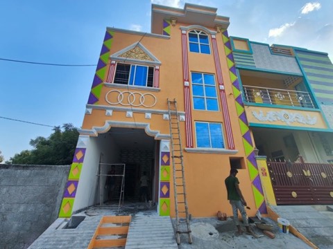 Workers on scaffolding painting a red and lime-green triangle and diamond facade design, VK Builders painting work