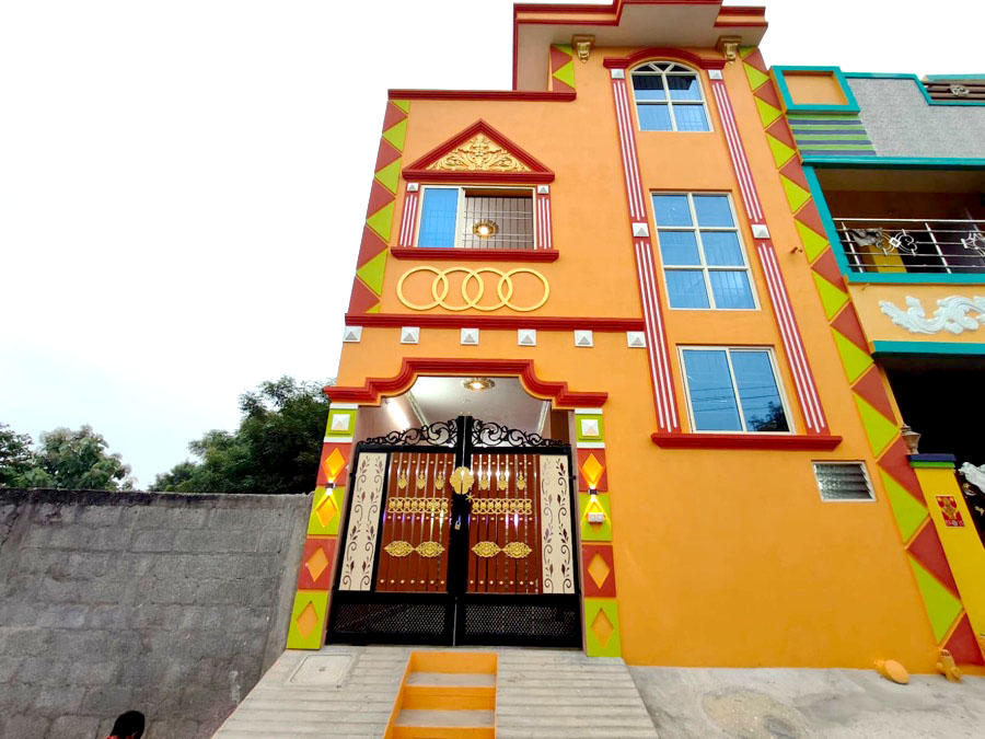 The same VK Builders house completed, orange and red facade with black metal gate